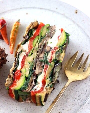 My PCOS Kitchen - Roasted Vegetable Terrine - A vegetable terrine on a white ceramic plate beside a gold bronze spoon.
