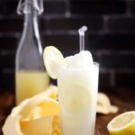 Sugar free frozen lemonade in a glass with some lemon slices and a straw.