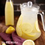 A large pitcher of lemonade with slices of lemons inside.