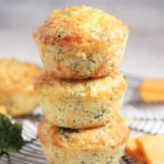 Cheddar broccoli muffins stacked on top of one another for a picture.