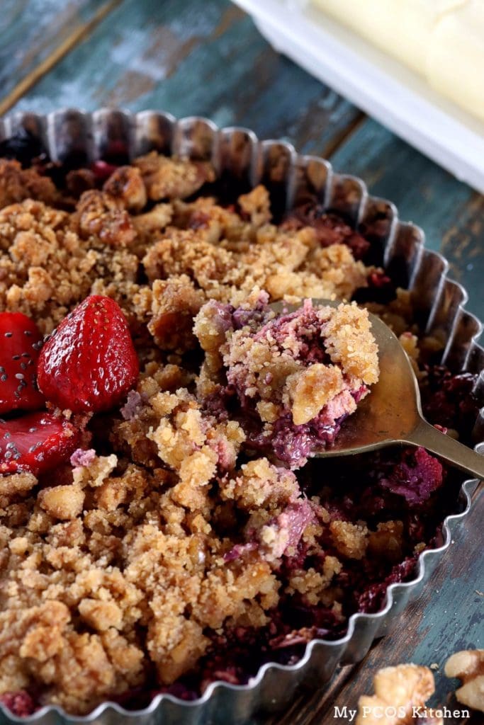 My PCOS Kitchen - Low Carb Strawberry Rhubarb Crisp - A brass spoon filled with a gluten-free and sugar-free crisp. Sweetened with stevia and the crumble is made of nuts.