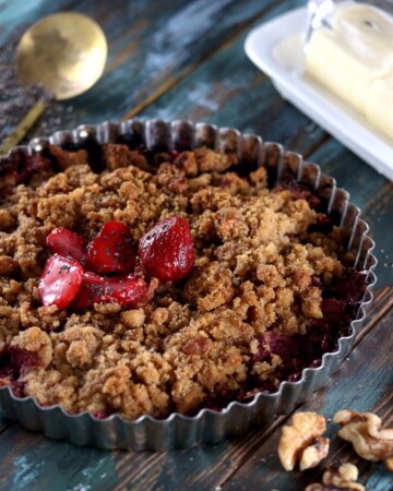 My PCOS Kitchen - Low Carb Strawberry Rhubarb Crisp - A delicious crispy crisp made with sugar-free strawberries and rhubarb. On a wooden blue surface and brass spoon in the back.
