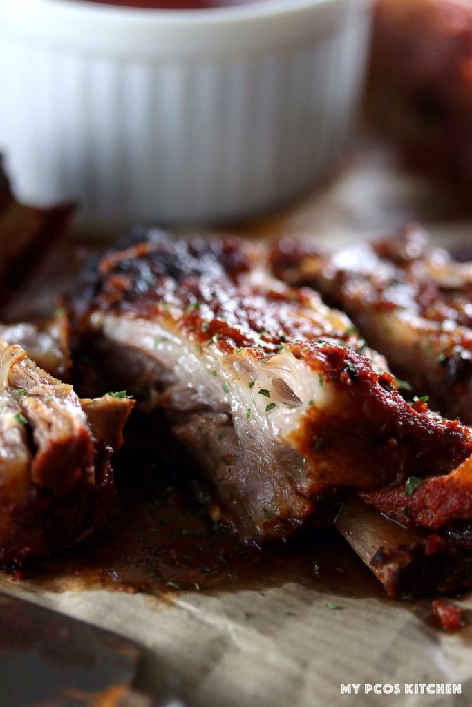 My PCOS Kitchen - Smoky BBQ Low Carb Ribs - Closeup shot of sliced ribgs with bbq sauce in the back.
