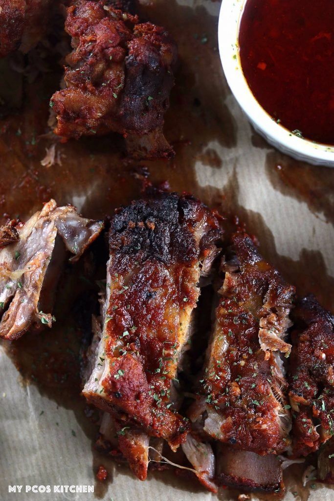 My PCOS Kitchen - Smoky BBQ Low Carb Ribs - Photography shot of ribs from above. Oil stains on parchment paper with homemade sugar-free bbq sauce.