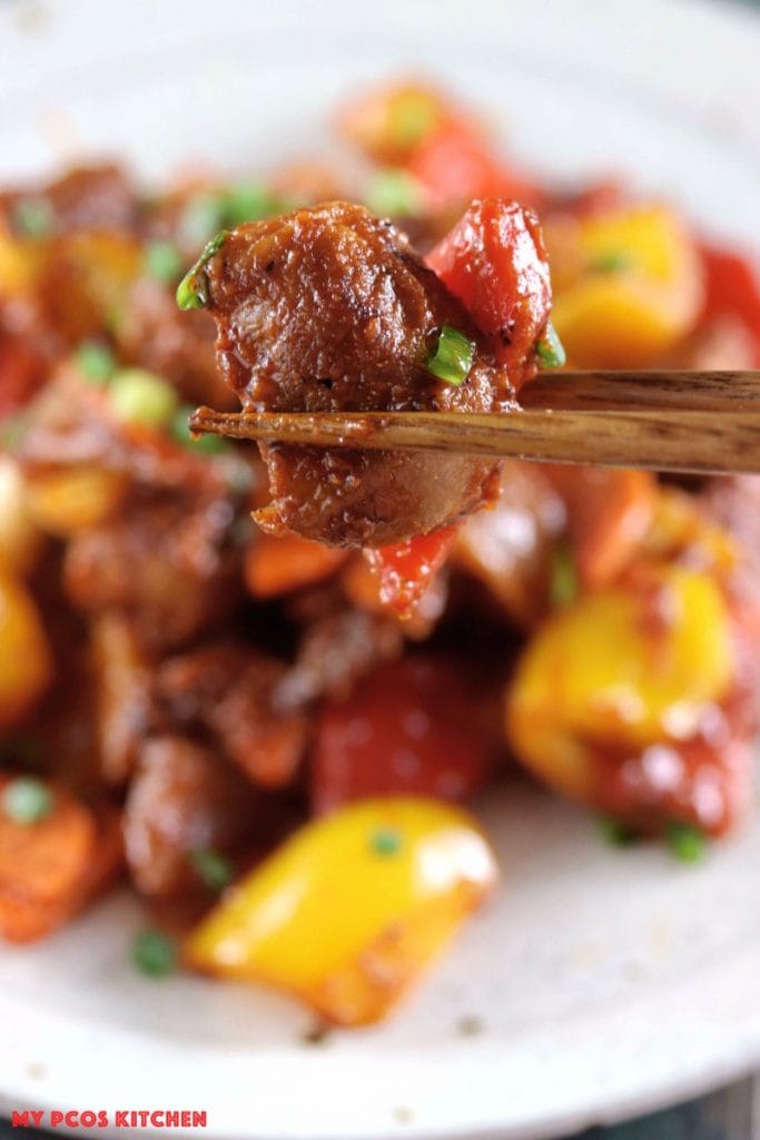 My PCOS Kitchen - Low Carb Paleo Sweet & Sour Pork - Chopsticks holding a piece of fried pork in a sugar-free and gluten-free sweet and sauce sauce.