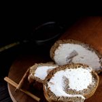 Keto Gingerbread Cake Roll - My PCOS Kitchen - Dark photography of a sugar-free roll cake over a wooden tray and cinnamon sticks on the side.