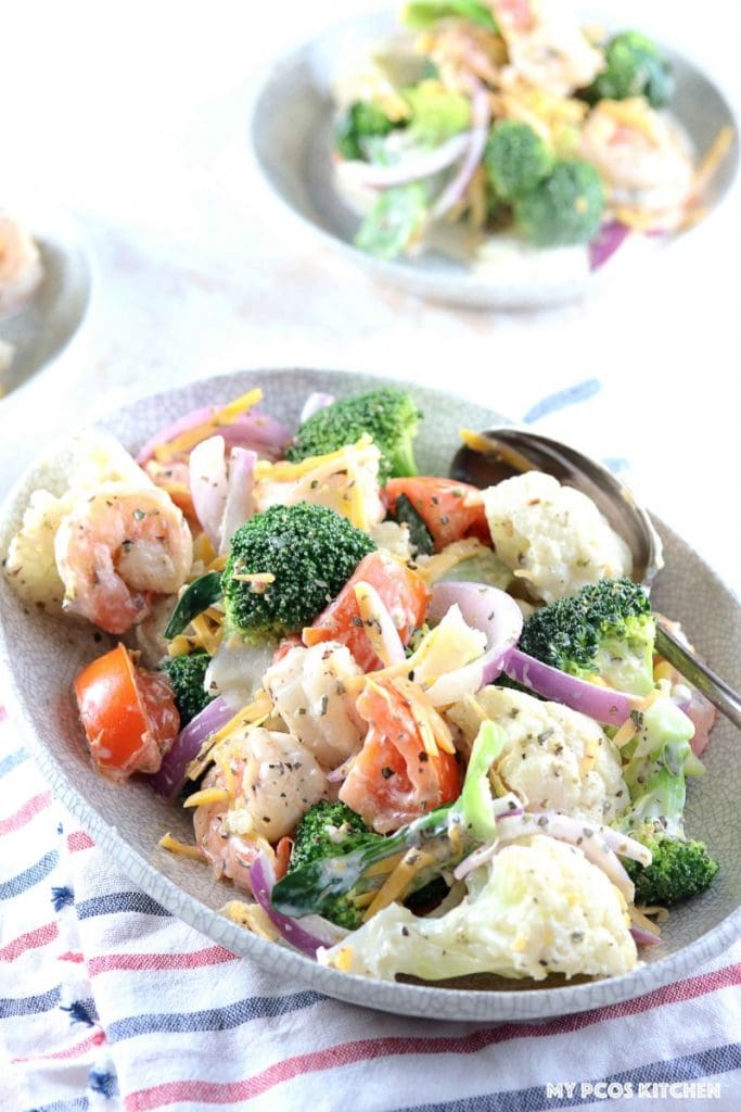 Amish Broccoli and Cauliflower Salad with Shrimps - My PCOS Kitchen - A delicious creamy salad made with healthy vegetables and shrimp. Two small bowls of salad in the background.
