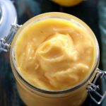 Low Carb Sugar Free Lemon Curd - My PCOS Kitchen - Creamy lemon custard in a glass jar with a lemon in the background.