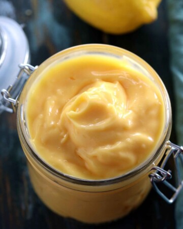 Low Carb Sugar Free Lemon Curd - My PCOS Kitchen - Creamy lemon custard in a glass jar with a lemon in the background.