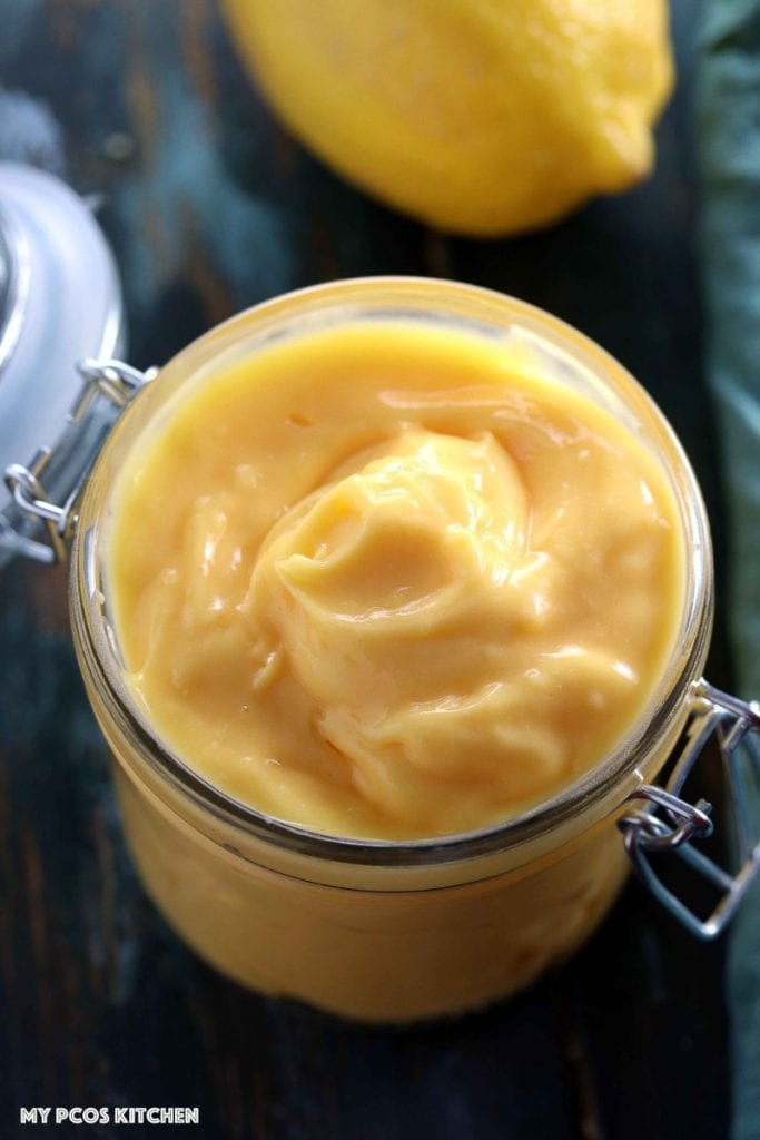 How to make Lemon Curd - Low Carb Sugar Free Lemon Curd - My PCOS Kitchen - Creamy lemon custard in a glass jar with a lemon in the background.