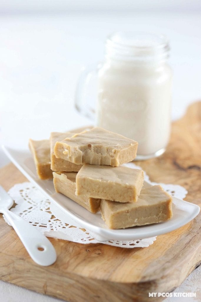 Low Carb Sugar Free Maple Fudge - My PCOS Kitchen - Creamy fudge over a small plate and a glass of almond milk in the background.