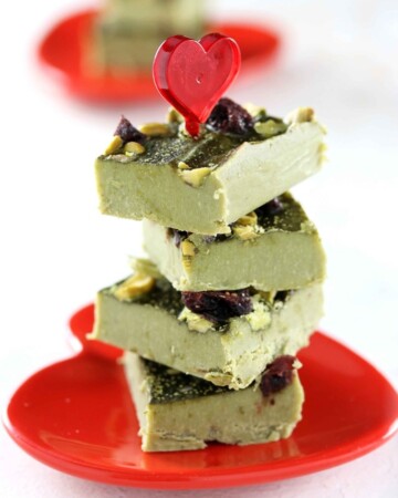 Low Carb Paleo Green Tea Matcha Fudge - My PCOS Kitchen - Green tea fat bombs stacked over one another over a red heart Valentine's Day plate.