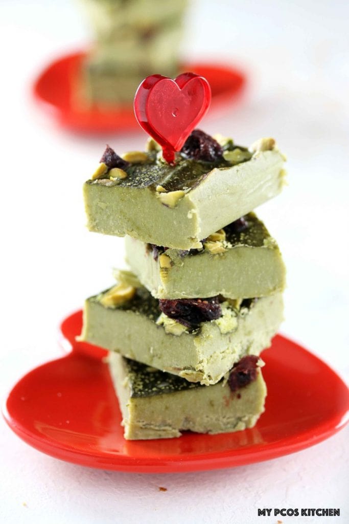 Low Carb Paleo Matcha Chocolate Fudge - My PCOS Kitchen - Green tea fat bombs stacked over one another over a red heart Valentine's Day plate.