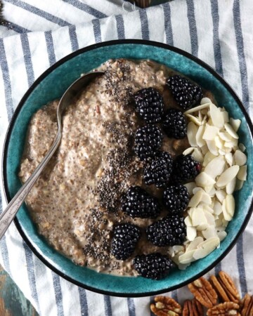 Maple Low Carb Oatmeal - My PCOS Kitchen - An overhead shot of chia seed paleo oatmeal with blackberries and almond slices in a blue bowl over a linen cloth.