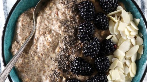 Maple Low Carb Oatmeal - My PCOS Kitchen - An overhead shot of chia seed paleo oatmeal with blackberries and almond slices in a blue bowl over a linen cloth.