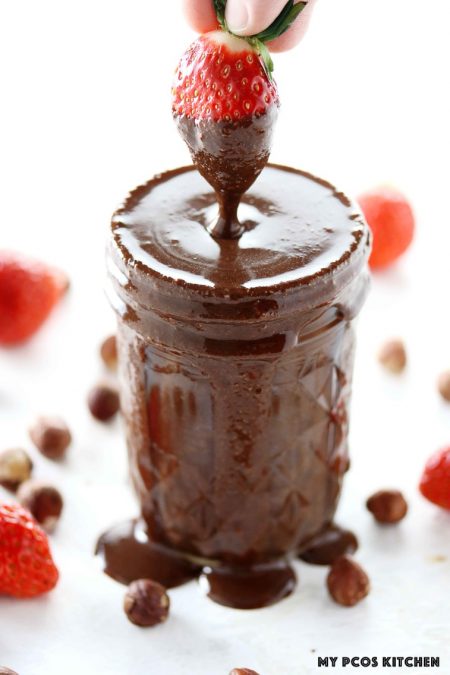 Sugar Free Nutella - My PCOS Kitchen - A strawberry is dipped in keto nutella in a glass jar.