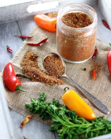 Low Carb Paleo Taco Seasoning - My PCOS Kitchen - A glass jar full of taco spice surrounded by chili peppers and cilantro.