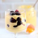 dairy free pastry cream made with coconut milk in a glass filled with berries with more custard in a bigger jar in the background.