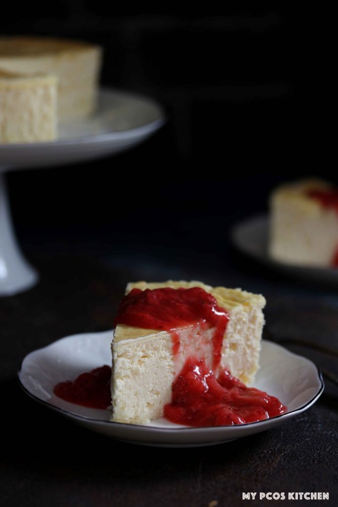 A low carb cheesecake sliced covered in a sugar free strawberry sauce.