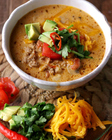 An easy keto taco soup recipe topped with low carb taco toppings serve in a white bowl.